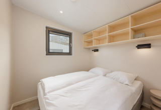 Minimalistisk soveværelse i Beach Houses Zandvoort 2, Holland, med to senge, hylder og vindue.