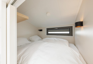 Lyst og hyggeligt soveværelse med skrå loft, vindue og hvidt sengetøj i Beach Houses Zandvoort 2.
