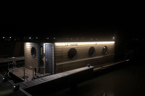 Een woonboot met de naam 'Wave' is verlicht 's nachts in Volendam Marina, Nederland.