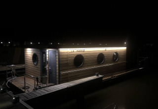 Ein Hausboot namens 'Wave' ist nachts im Volendam Marina in den Niederlanden beleuchtet.