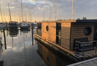 Péniche à Volendam Marina aux Pays-Bas, flottant sur l’eau au coucher du soleil, entourée de voiliers.