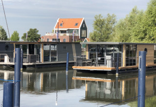 Péniches modernes amarrées à la marina de Volendam aux Pays-Bas, maisons traditionnelles en arrière-plan.