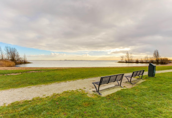 Bancs face au lac à Volendam Marina, Pays-Bas, lors d’une journée calme au ciel nuageux.