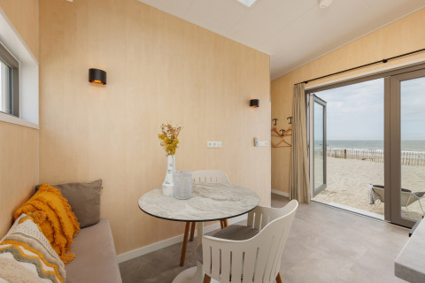 Lyst interiør i Beach Houses Zandvoort 2 med udsigt til sandstrand og hav gennem åbne døre.
