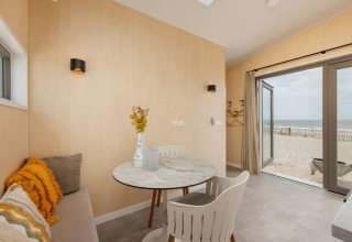 Lyst interiør i Beach Houses Zandvoort 2 med udsigt til sandstrand og hav gennem åbne døre.