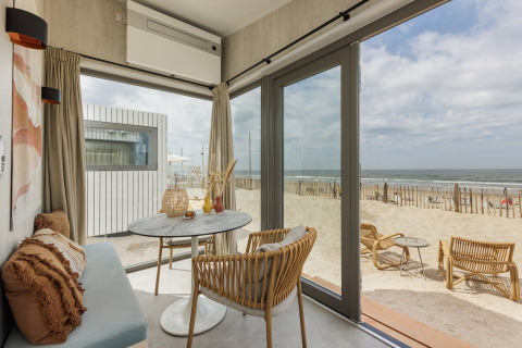 Lyst strandhusinteriør med havudsigt fra store vinduer, Zandvoort Beach Houses i Holland.