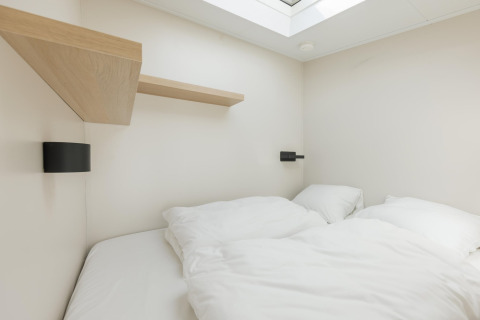 Moderne soveværelse på Beach Houses Zandvoort 3 i Holland, med hvidt sengelinned og ovenlys vindue.