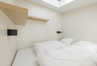 Moderne soveværelse på Beach Houses Zandvoort 3 i Holland, med hvidt sengelinned og ovenlys vindue.