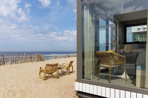 Udsigt fra et strandhus ved stranden, med kurvemøbler udenfor og indvendig, Zandvoort, Holland.