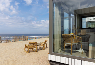 Udsigt fra et strandhus ved stranden, med kurvemøbler udenfor og indvendig, Zandvoort, Holland.