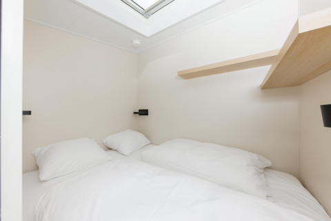 Lyst og minimalistisk soveværelse med dobbeltseng og hylde, set i Beach Houses Zandvoort 3, Holland.