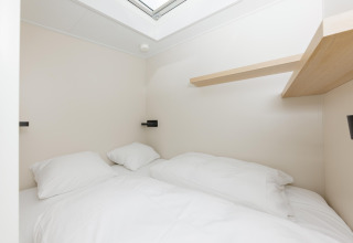 Lyst og minimalistisk soveværelse med dobbeltseng og hylde, set i Beach Houses Zandvoort 3, Holland.