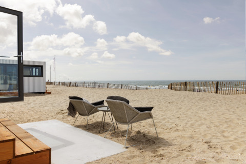 Strandhus Zandvoort 3 i Holland med udsigt over stranden, to stole og et lille bord under åben himmel.
