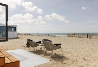 Strandhus Zandvoort 3 i Holland med udsigt over stranden, to stole og et lille bord under åben himmel.