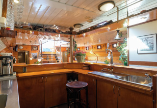 Gezellige keuken op woonboot in Leiden met houten panelen, bar en veel licht dicht bij het centrum.