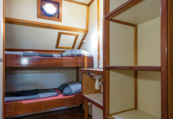 Habitación con literas, estantería y ventana redonda en una casa flotante en Leiden, Países Bajos.