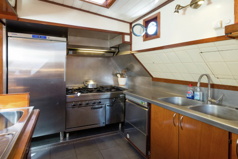Moderne keuken op een woonboot in Leiden met RVS apparatuur, dubbele spoelbak en gasfornuis.