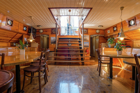 Interieur van een woonboot in Leiden, Nederland, met houten inrichting en ronde patrijspoorten.
