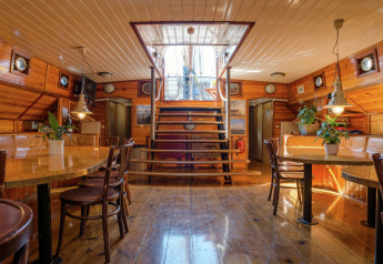 Interior de una casa flotante en Leiden, Países Bajos, con paredes de madera y ventanas redondas.