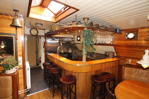 Gezellige keuken en bar op woonboot in Leiden, Nederland, met houtafwerking en dakraam.