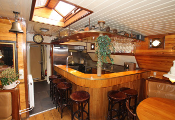 Gemütliche Küche und Bar auf einem Hausboot in Leiden, Niederlande, mit Holzverkleidung und Dachfenster.