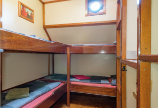 Lichte kajuit met vier houten stapelbedden op een woonboot in Leiden, Nederland.