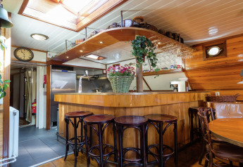 Gemütliche Innenansicht einer Hausboot-Bar in Leiden, Niederlande, mit Holzdekor und Barhockern.