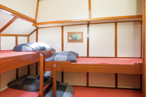 Kamer met twee houten stapelbedden en rood beddengoed op een woonboot in Leiden nabij het centrum.