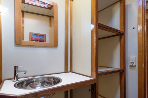 Badkamer op een woonboot in Leiden met moderne wasbak, spiegel, open rekken en stopcontact.