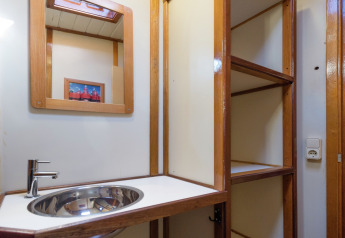 Baño en una casa flotante en Leiden con lavabo moderno, espejo, estanterías y enchufe.
