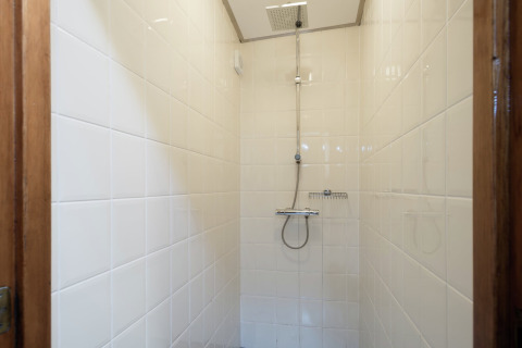 Binnenzicht van een douche met witte tegels op een woonboot dichtbij centrum en musea van Leiden.
