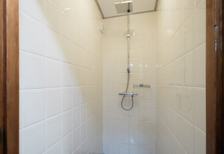 Binnenzicht van een douche met witte tegels op een woonboot dichtbij centrum en musea van Leiden.