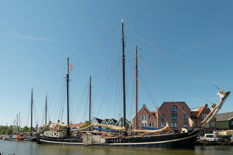 Grote woonboot genaamd Boat in Leiden, aangemeerd nabij het stadscentrum en musea onder een blauwe lucht.