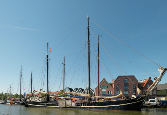 Grote woonboot genaamd Boat in Leiden, aangemeerd nabij het stadscentrum en musea onder een blauwe lucht.