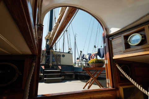 Uitzicht vanuit een woonboot in Leiden, Nederland, met scheepsmasten en een tafel met bloemen.