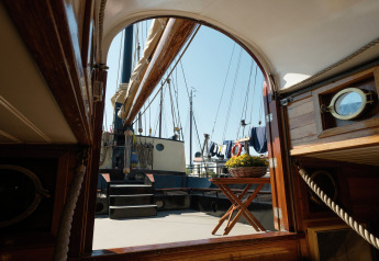 Blick von einer Hausbootkabine in Leiden, Niederlande, auf Deck mit Segelmasten und Blumen.