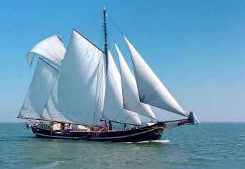 Gran barco de vela con velas blancas navega por Leiden, Países Bajos, cerca del centro de la ciudad y museos.