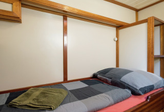 Einzelbett auf Hausboot in Leiden, mit Holzakzenten sowie kariertem Bettzeug und Handtüchern.