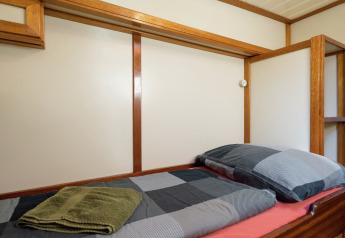 Einzelbett auf Hausboot in Leiden, mit Holzakzenten sowie kariertem Bettzeug und Handtüchern.