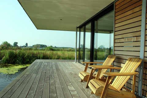 To træstole på dækket af husbåden Watervilla de Blauwe Reiger med udsigt over naturen i Holland.