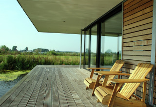To træstole på dækket af husbåden Watervilla de Blauwe Reiger med udsigt over naturen i Holland.