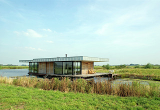 Moderne husbåd ved navn Watervilla de Blauwe Reiger på vandet i det hollandske landskab.