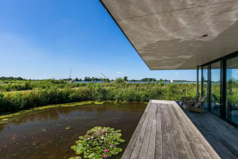 Udsigt fra husbåd Watervilla de Blauwe Reiger med træterrasse, dam og naturudsigt i Holland.