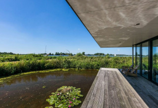 Udsigt fra husbåd Watervilla de Blauwe Reiger med træterrasse, dam og naturudsigt i Holland.