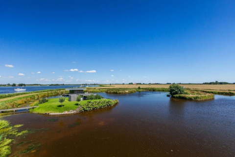 Smuk udsigt over Watervilla de Blauwe Reiger husbåd ved vandet i Holland under en klar blå himmel.