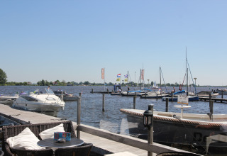 Udsigt fra Watervilla de Blauwe Reiger i Holland med både, havn og udendørs siddeplads i solskin.