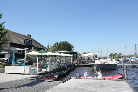 Udsigt over Watervilla de Blauwe Reiger i Holland med terrasse, både og klart himmelvejr ved vandet.