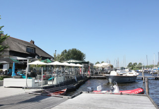 Udsigt over Watervilla de Blauwe Reiger i Holland med terrasse, både og klart himmelvejr ved vandet.
