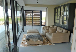 Moderne stue på husbåd Watervilla de Blauwe Reiger i Holland med store vinduer og beige møbler.
