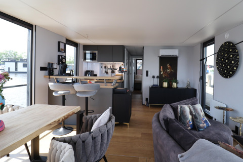 Modern interieur van woonboot 'Kohlenpott' in Nederland, met keuken, salon en zicht op het water.